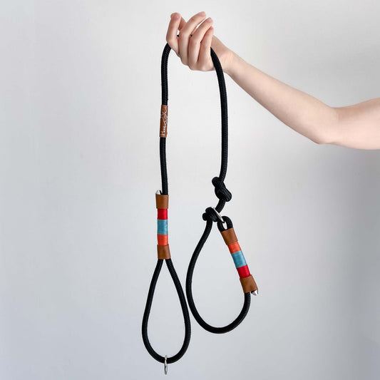 Rooibos slip lead in black rope with red, teal and coral whipping, held in a hand